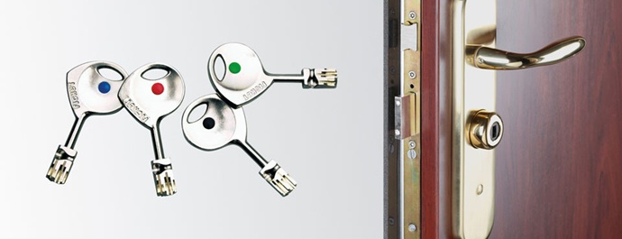 Llaves Fichet clásicas con distintivos de color junto a herrajes dorados y cerradura multipunto de puerta acorazada.