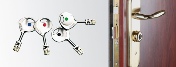 Llaves Fichet clásicas con distintivos de color junto a herrajes dorados y cerradura multipunto de puerta acorazada.